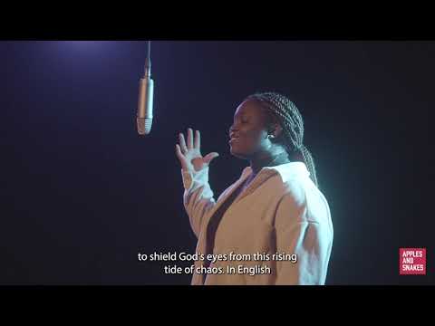 Screenshot from a video of Eileen speaking into a microphone in a dark room with purple and blue lighting