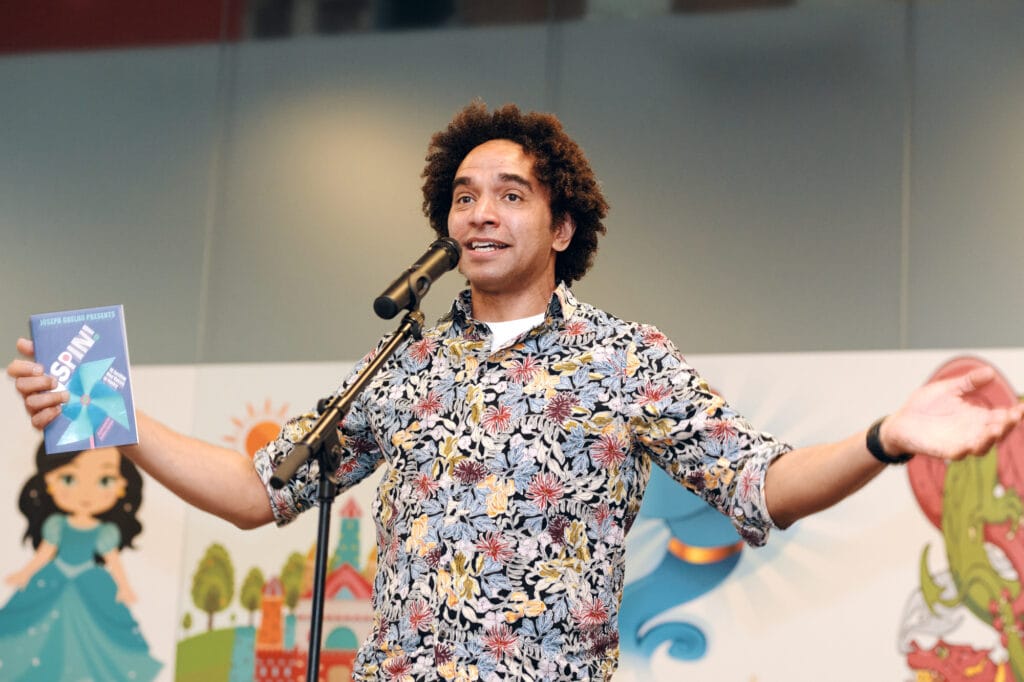 Joseph Coelho on stage in a bright patterned and multicolour shirt