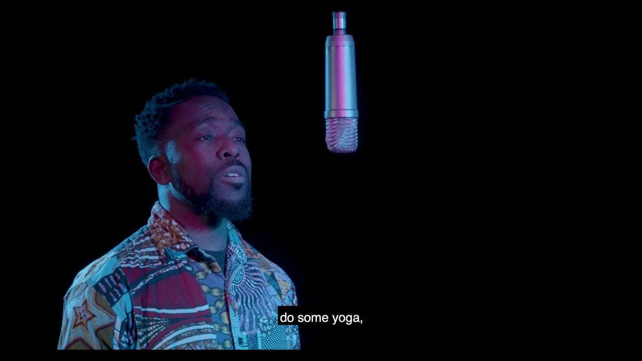 Man in a patterned shirt speaking in to a microphone