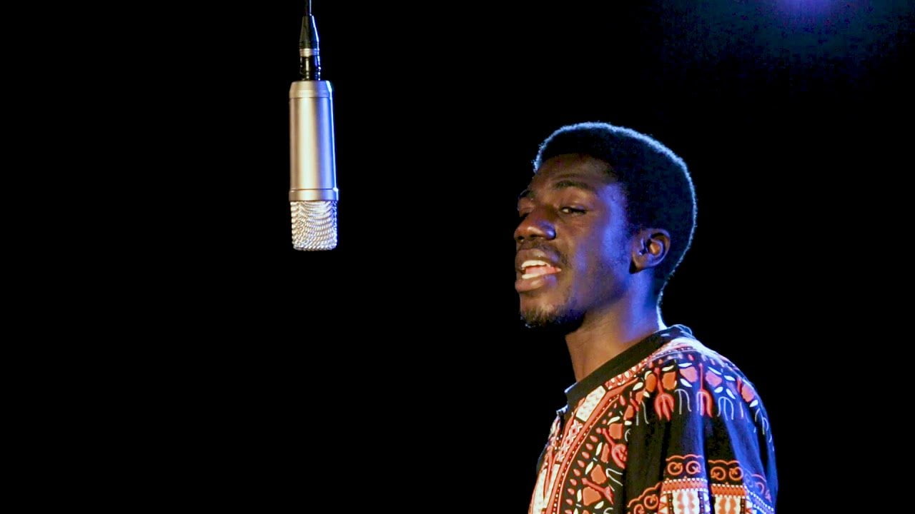 Man in patterned top speaks into microphone