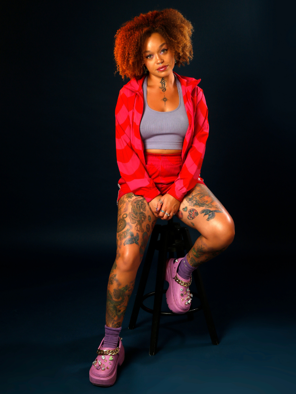 AFLO. in a red cardigan and red skit, pink shoes and grey vest top