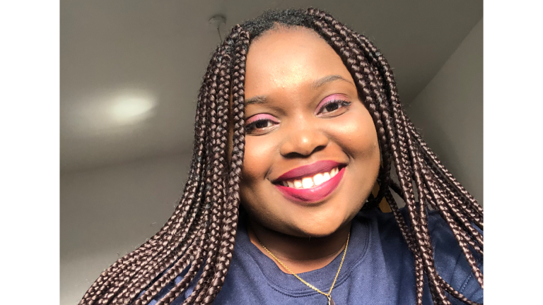 A woman with braided hair and pink lipstick smiles
