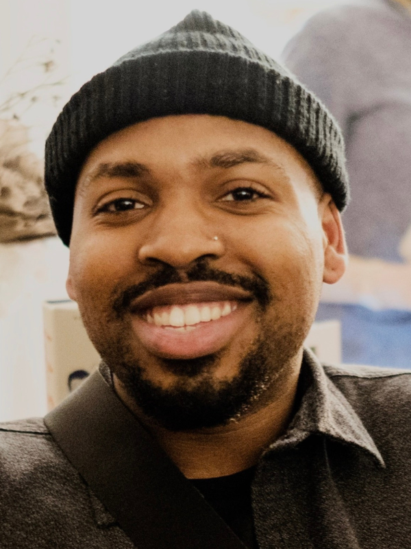 Kareem Parkins-Brown with a green beanie and green shirt, smiling