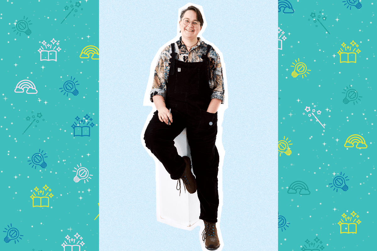 An image of poet Linden McMahon, Linden has short brown hair and wears glasses. They have a flowery shirt and black dungarees. The sit on a white pedestal and were black boots.