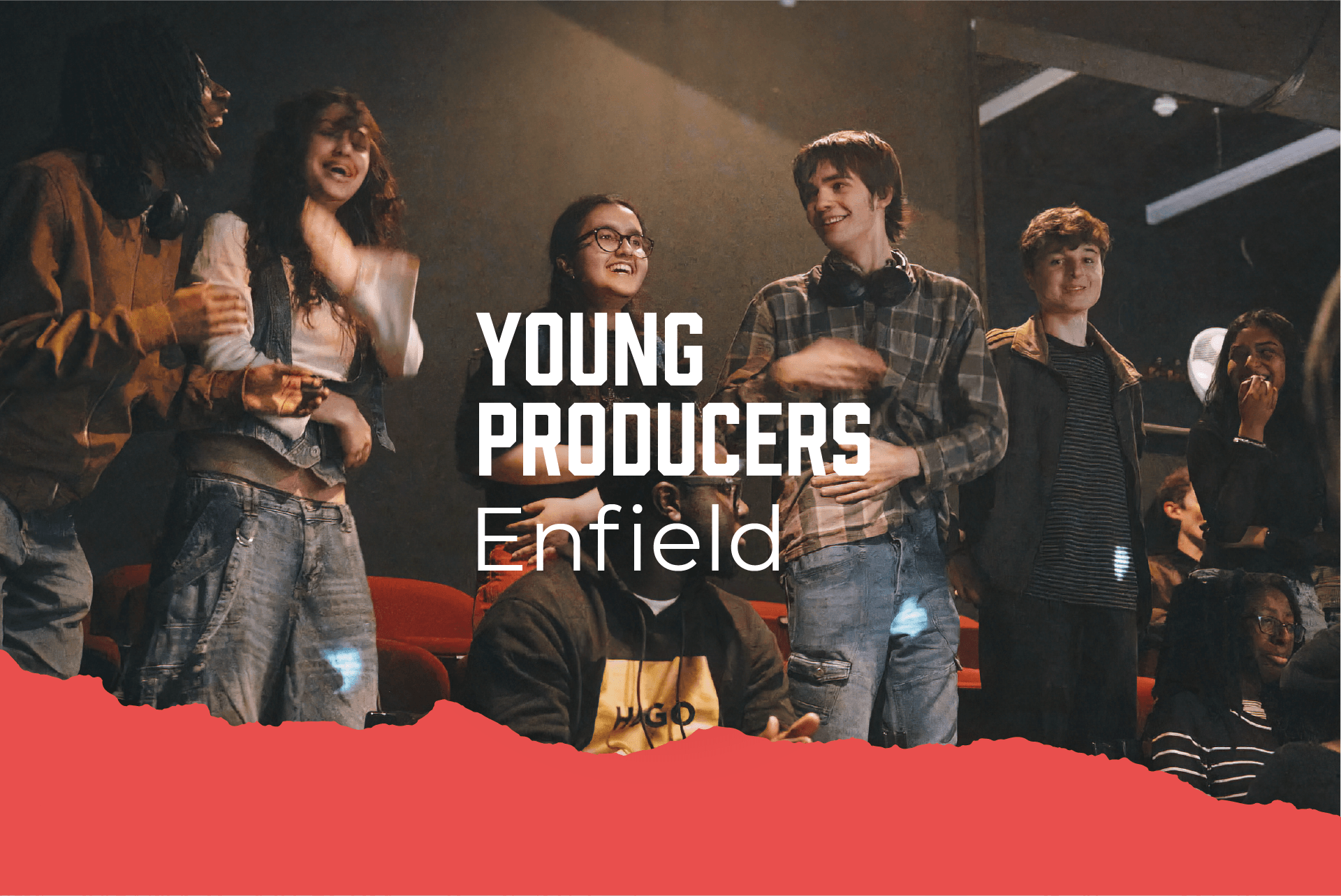 A group of young adults smiling together in a theatre setting