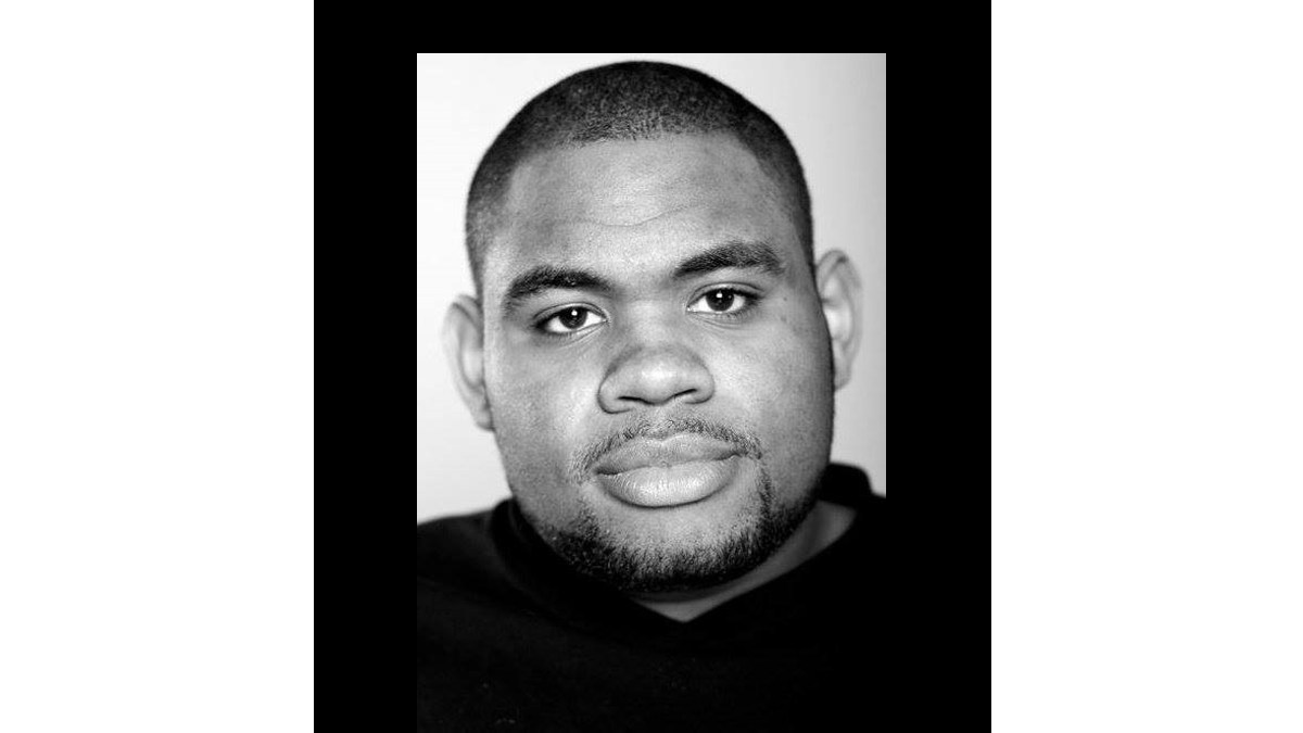 A man with shaved head and black hoodie