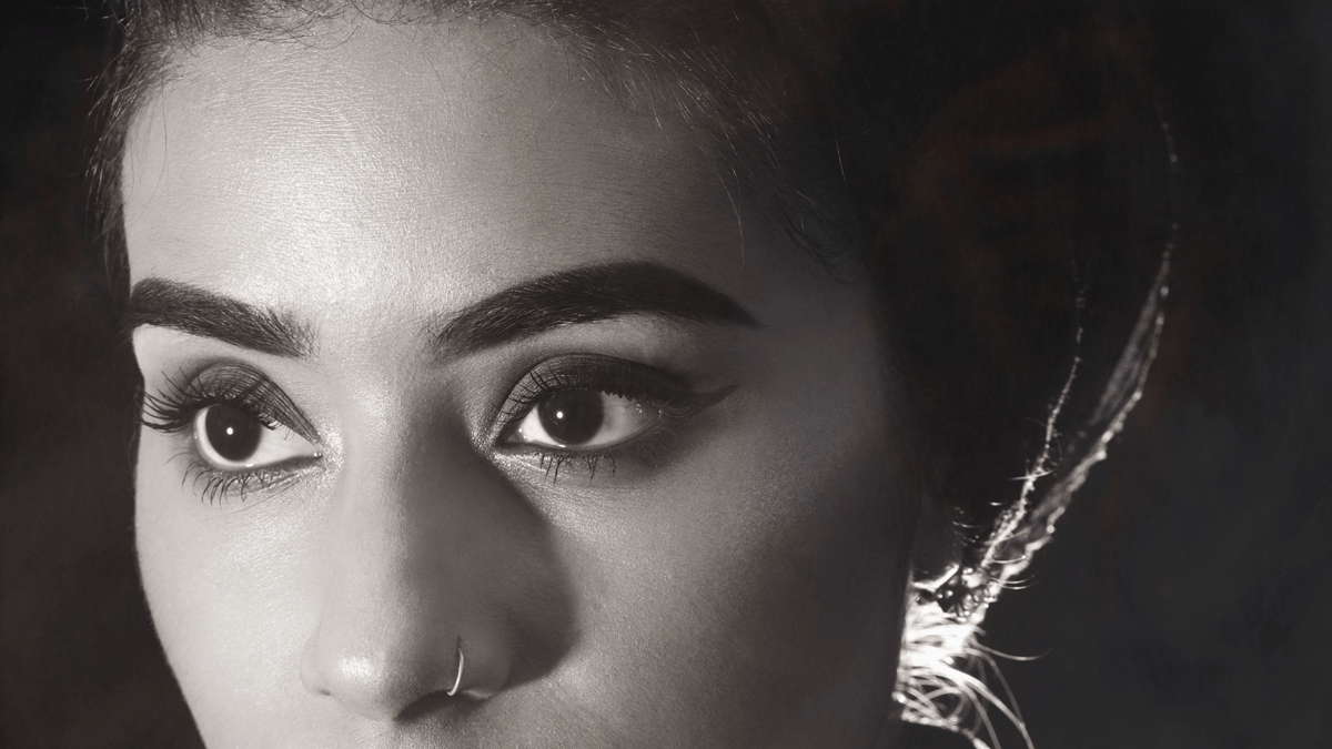 A striking woman with dark eye brows and ring in her nose.